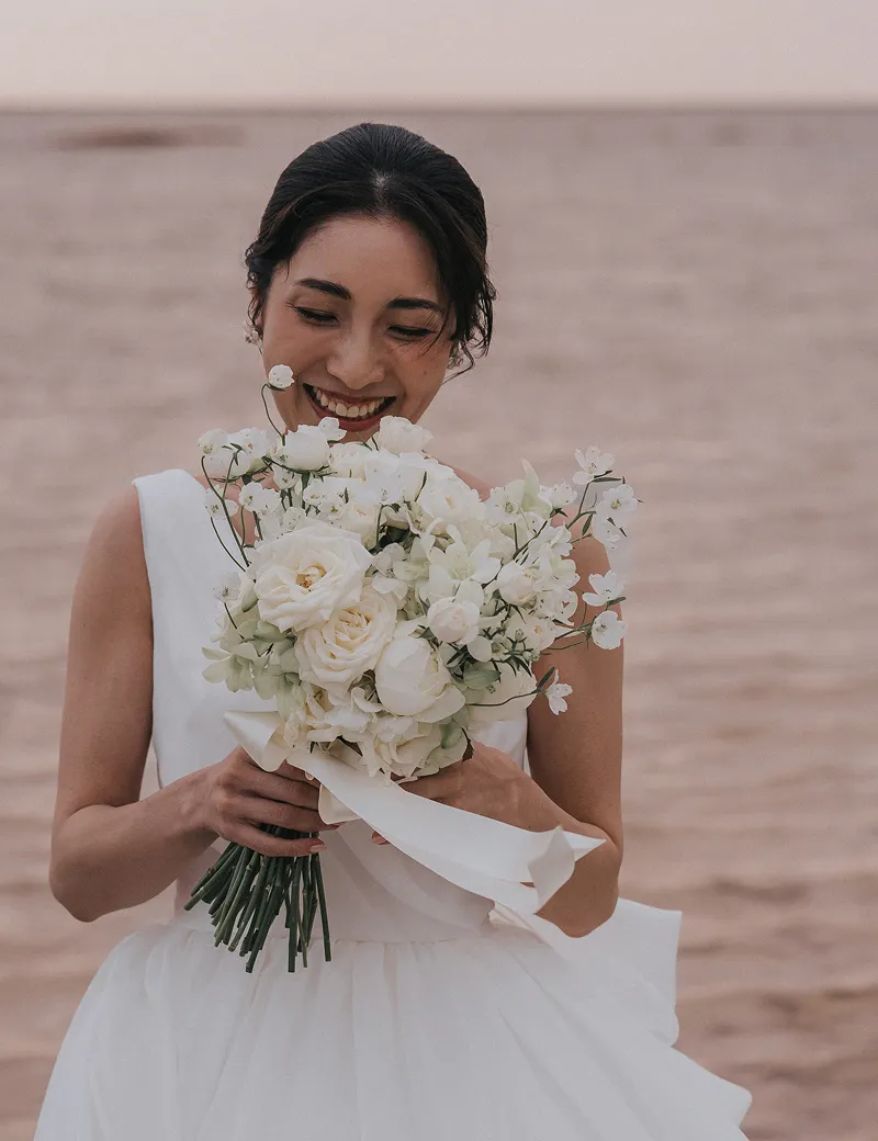 ブーケを胸元に抱き、柔らかな笑顔を浮かべるLisのドレス姿の新婦